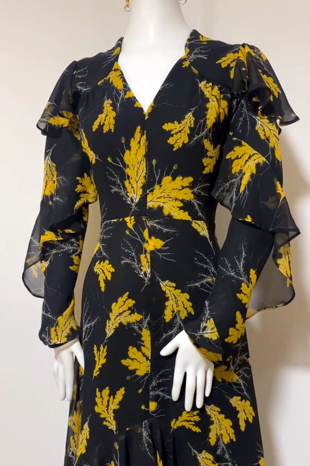 Angie dress on a mannequin Beautiful Oak leaf black and yellow chiffon print maxi dress with spiral frill sleeves and cascading frill at the lower part of the skirt.