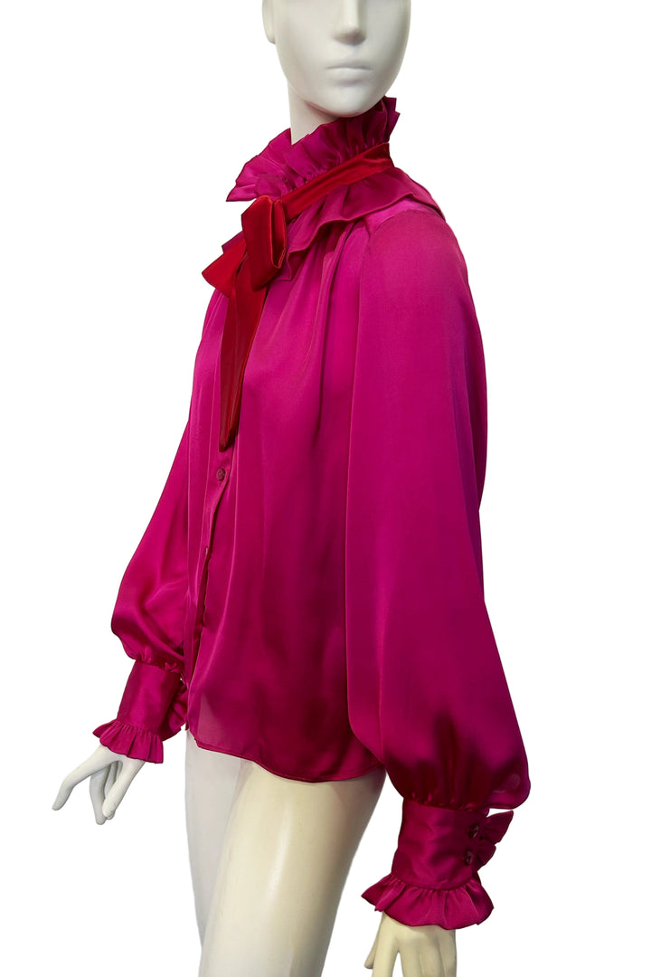 Mannequin wearing the Estelle Jazz satin blouse by Holly Campbell. A bright pink blouse with a large red bow against a white background