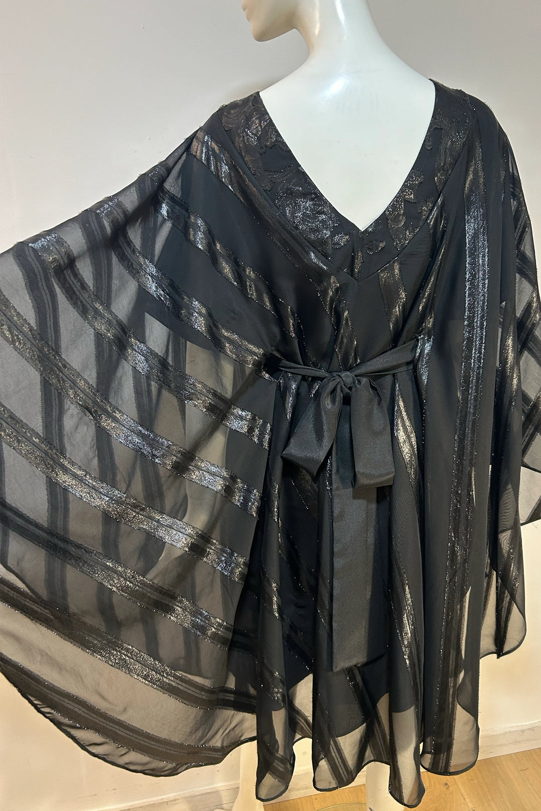 back view of This Lucie black gloss stripe Kaftan is a beautiful, dramatic yet effortless design with a flowing curved chiffon jacquard overlay and an attached black satin slip underneath.