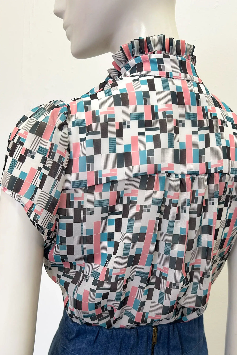 Mannequin wearing Holly Cambell Studio patterned blouse with cap sleeve with geometric design on a plain background