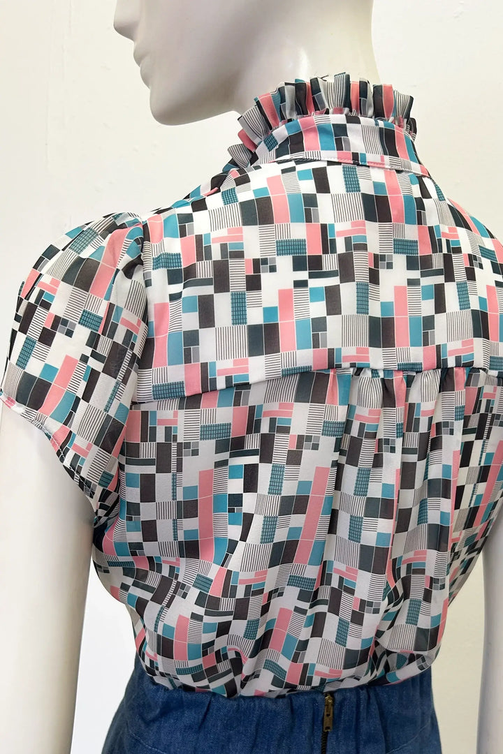 Mannequin wearing Holly Cambell Studio patterned blouse with cap sleeve with geometric design on a plain background