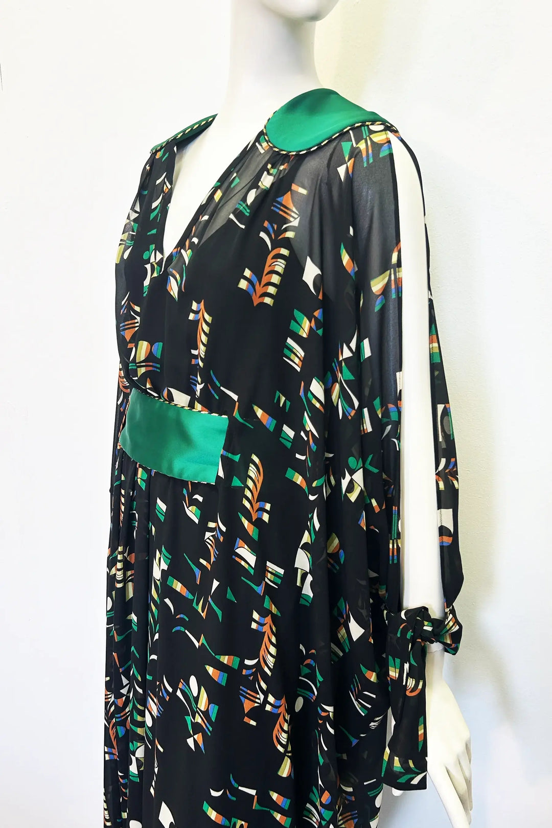 Mannequin wearing a black kaftan with colourful pattern and green accents on a white background. Handmade by Holly Campbell Studio in Edinburgh.