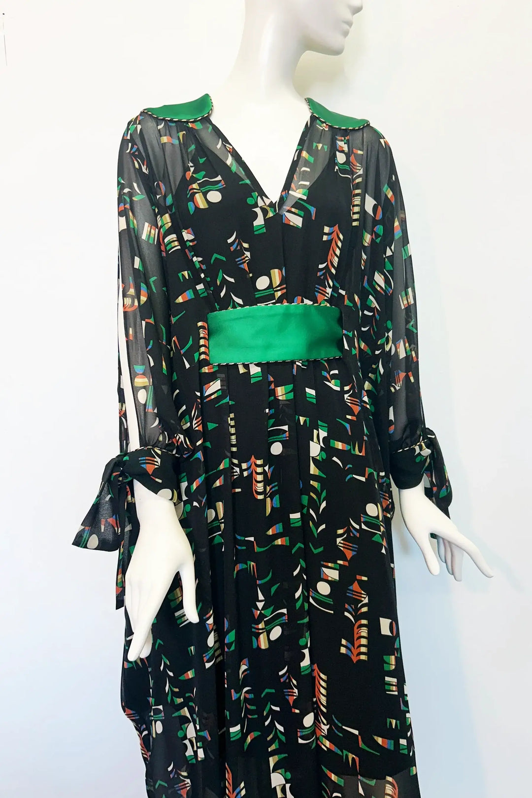 Mannequin wearing a black kaftan with colourful pattern and green accents on a white background. Handmade by Holly Campbell Studio in Edinburgh.